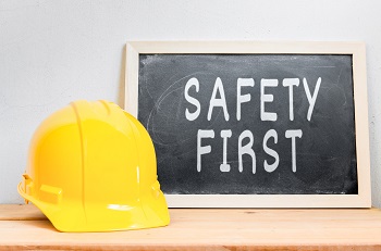 yellow hard hat next to a chalkboard that says safety first